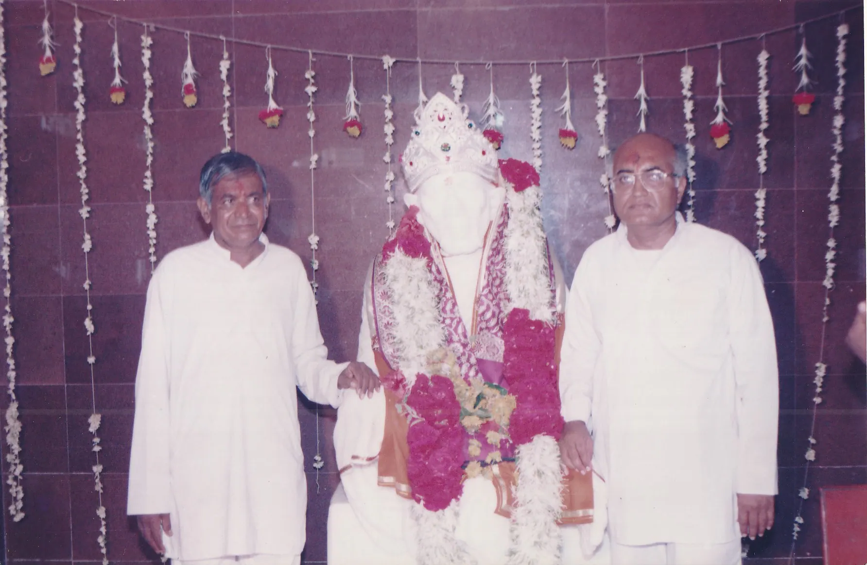 Param Pujya Shri Dhondiram Baba Chavan standing beside a decorated Shree Sai Baba murti