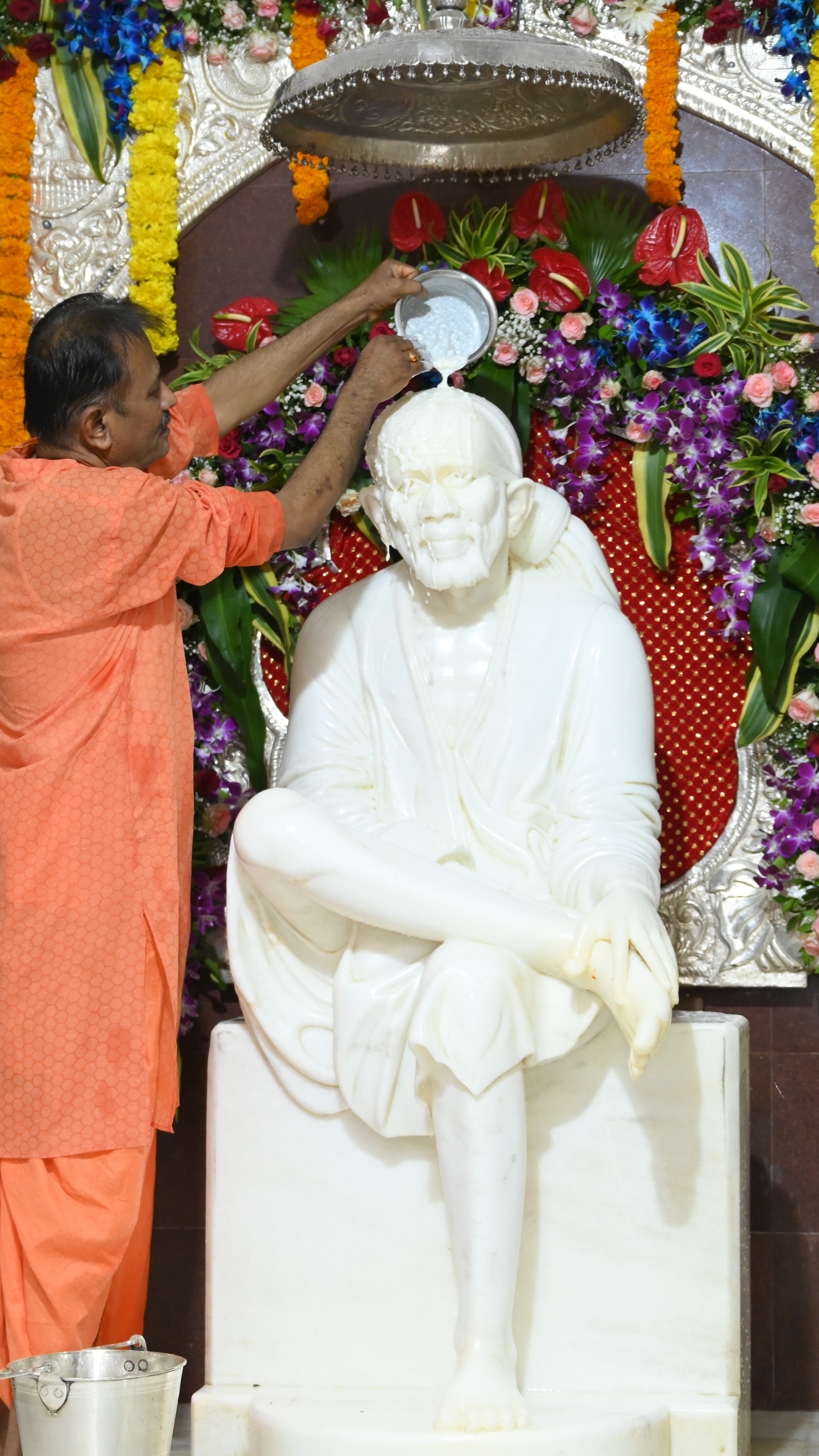 Devotee pouring milk during Sai Baba murti abhishek