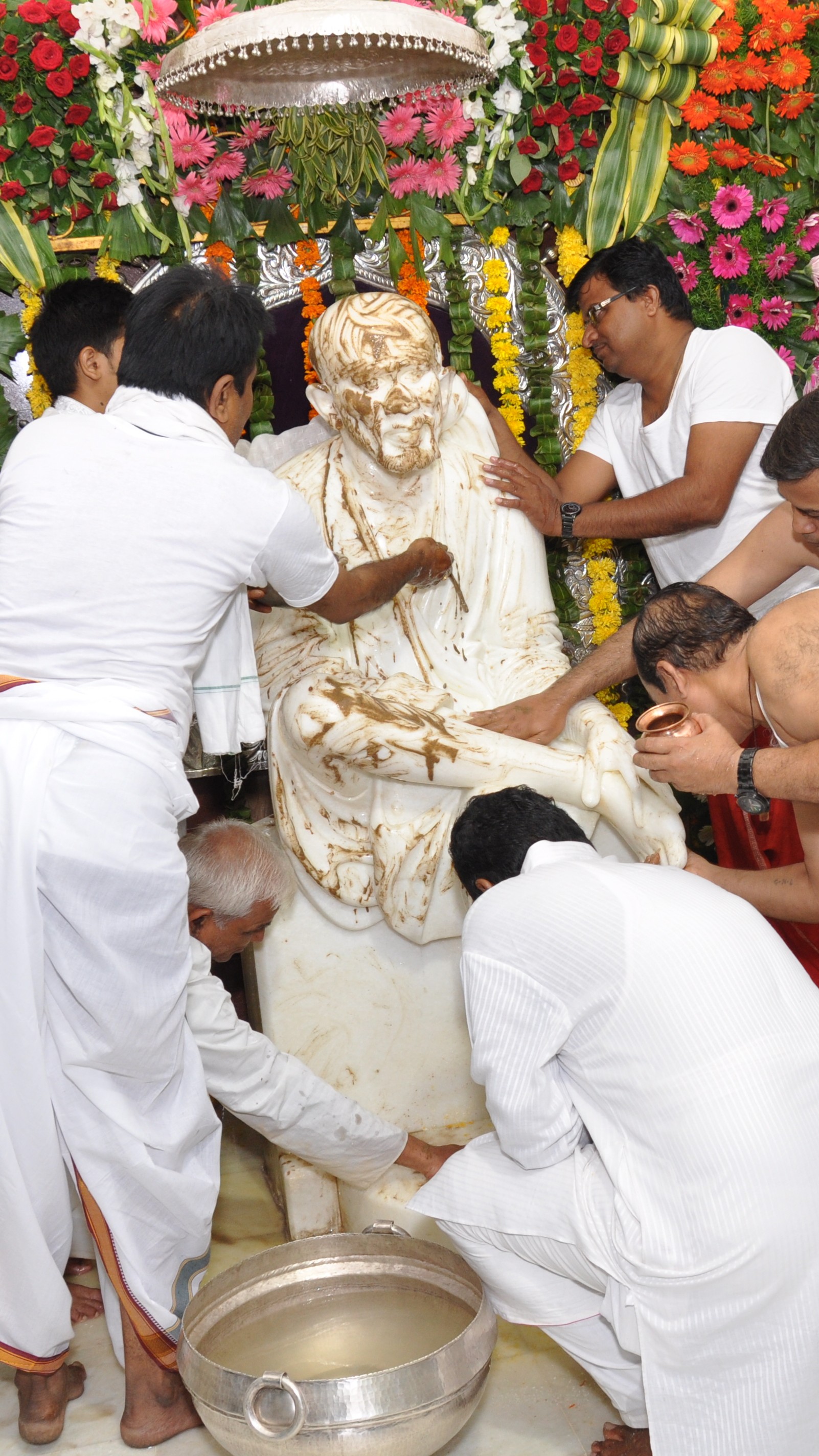 Devotees performing abhishek seva for Sai Baba murti