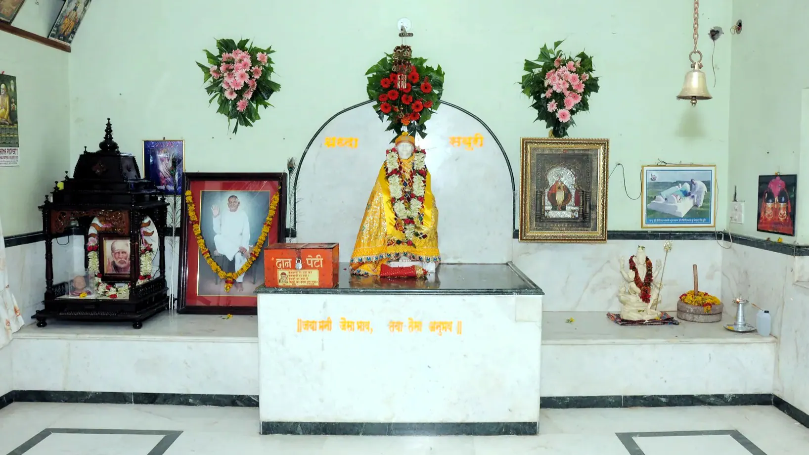 Gurusthan interior with Sai Baba murti and framed devotional photographs