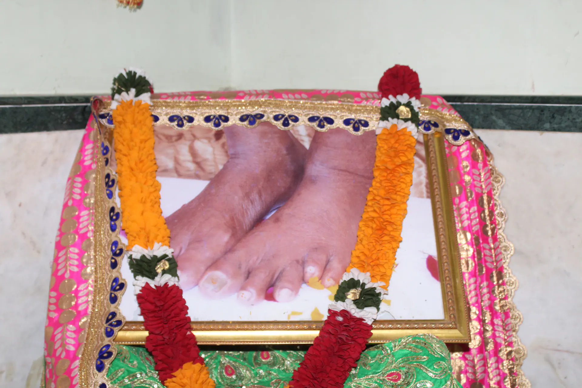 Framed paduka photograph decorated with garlands and cloth inside Gurusthan