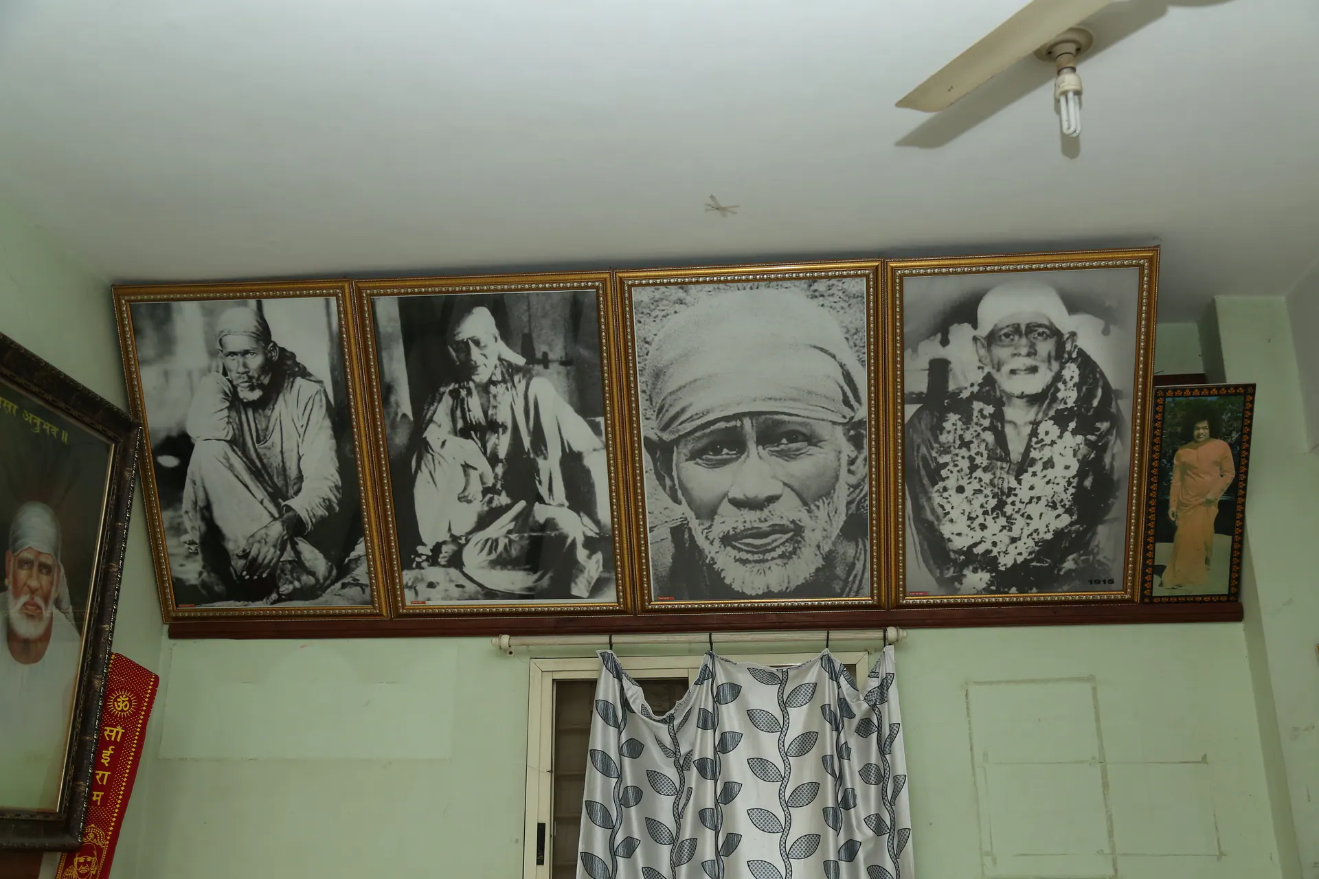 Framed black and white Sai Baba photographs displayed high on the Gurusthan wall